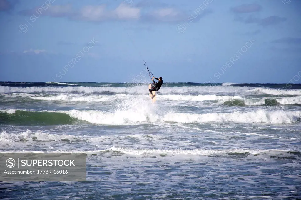 Male kitesurfer jumps the wave on his board.
