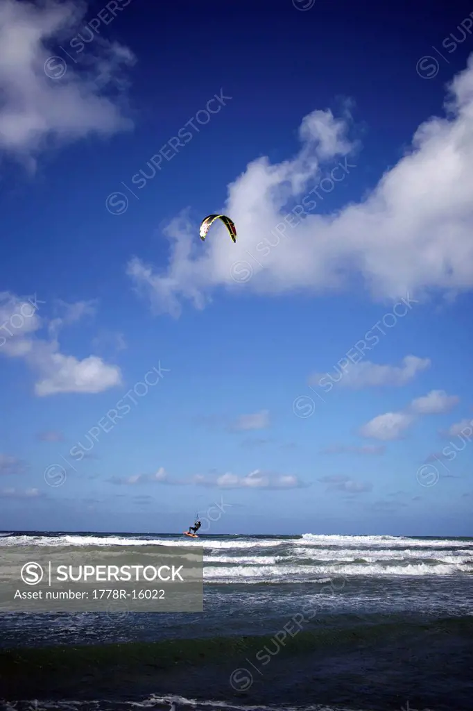 Male kitesurfer about to land in the water right after jumping on his board.