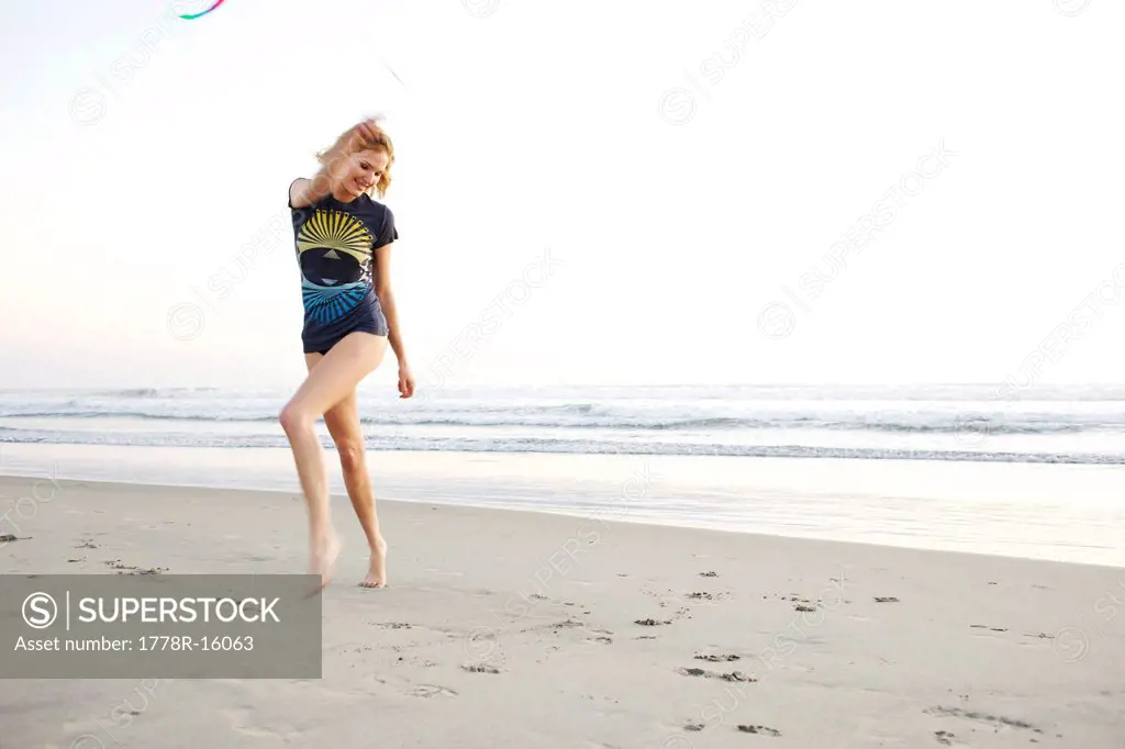 Young female plays with a colorful ribbon at the beach.