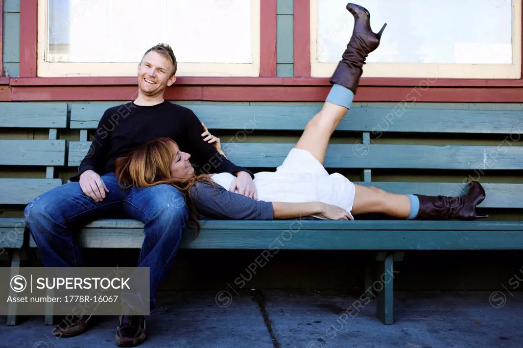Couple sits on a bench and smile.