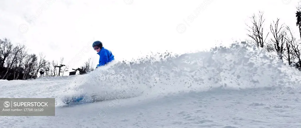 A female snowboarder kicks up snow in New Hampshire.