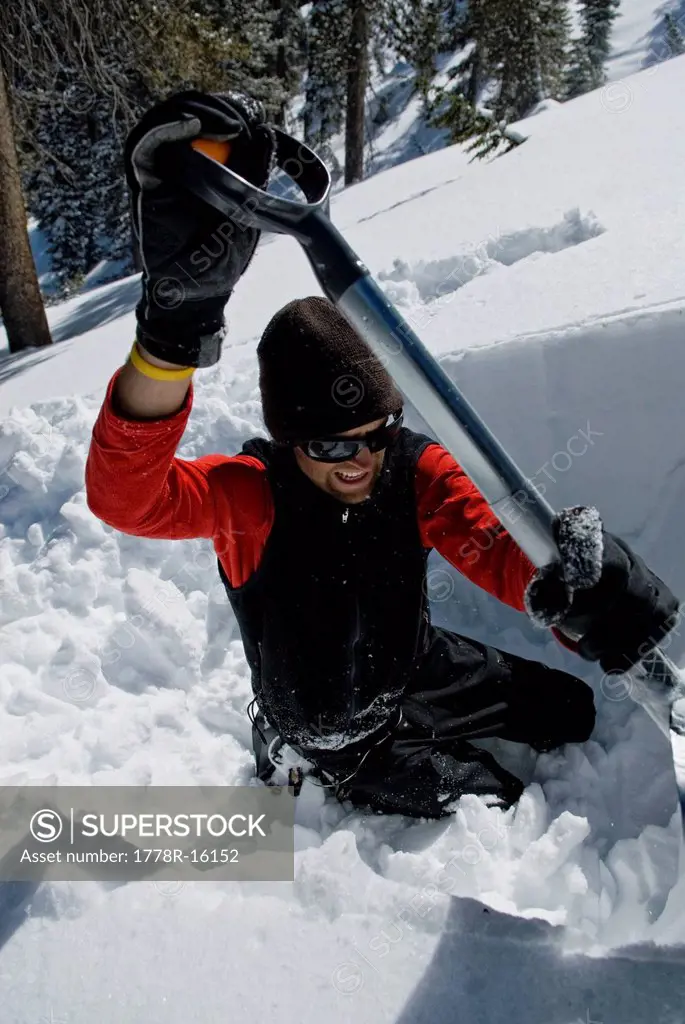 A young man digs an avalanche pit to examine the snow pack and determine the avalanche danger, in the Lake Tahoe backcountry, Nevada.