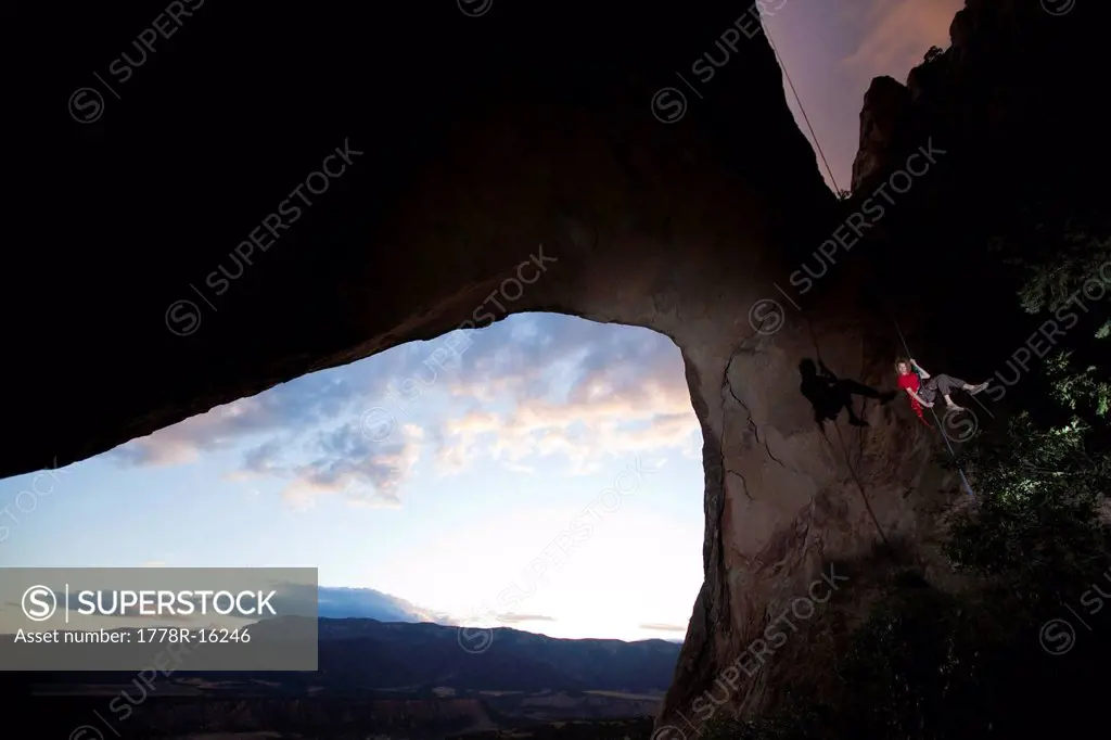 Young adult male rappels down an arch in Colorado.