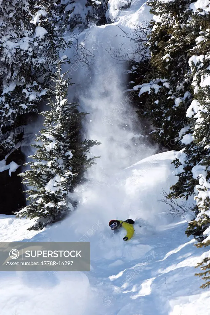 A snowboarder jumps off a cliff into powder in Colorado.