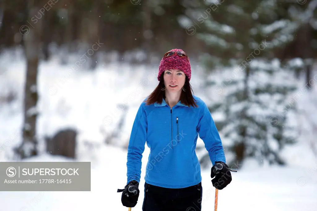 A woman cross country skis on a trail in a forest.