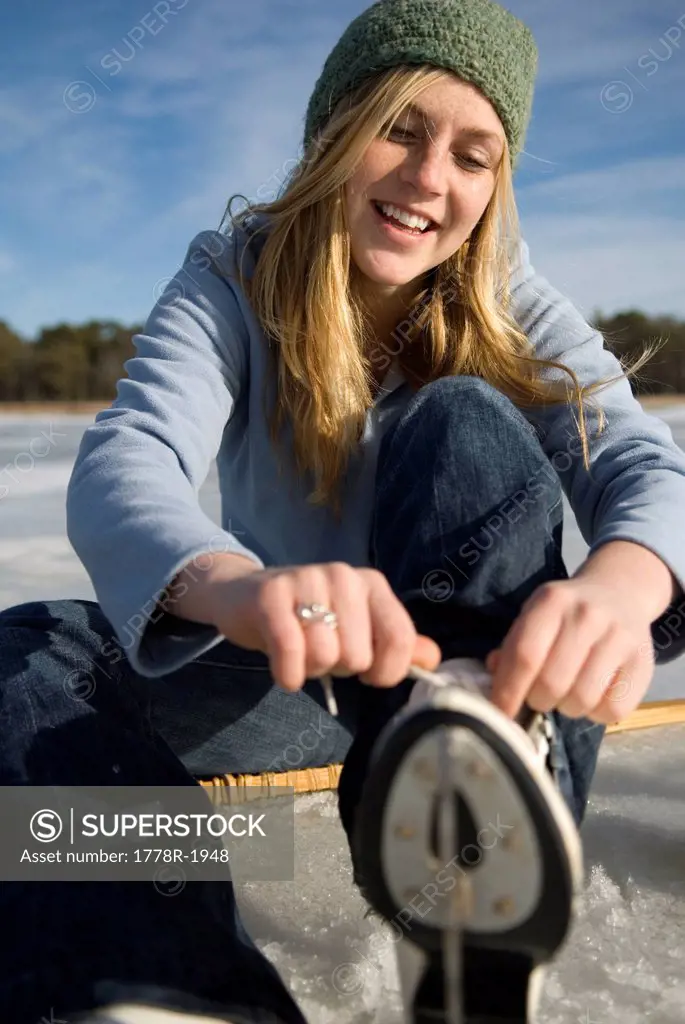 Young woman laces up ice skates.