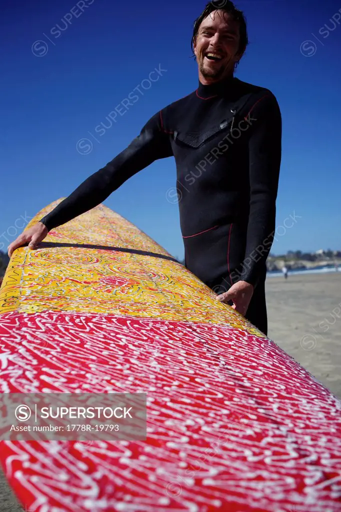 Male surfer shows his colorful surfboard.