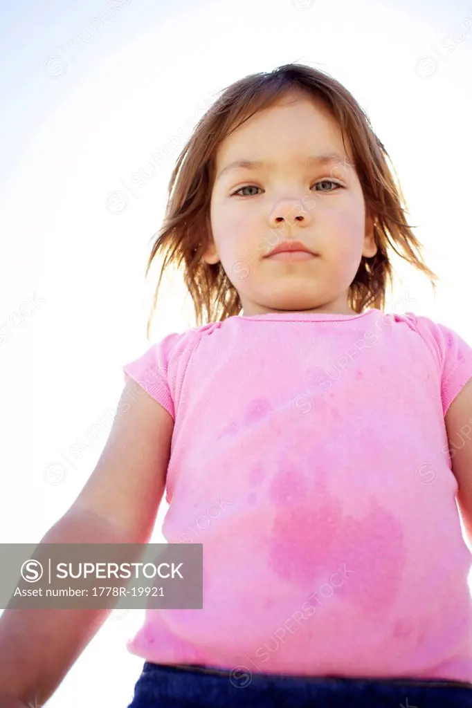 Young girl wearing pink looks down at the camera.