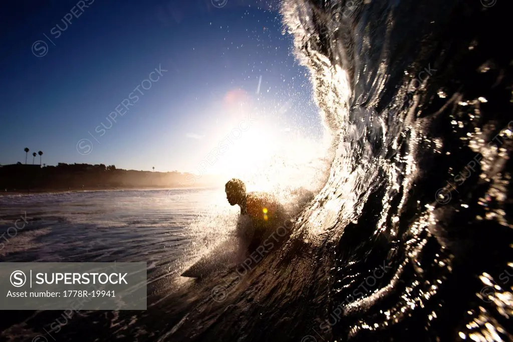 A male surfer pulls into a barrel at Zuma beach in Malibu, California.