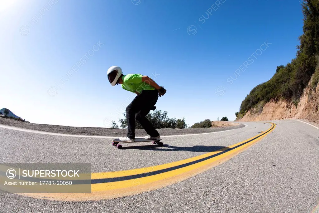 A downhill skateboarder rides down a steep mountain.