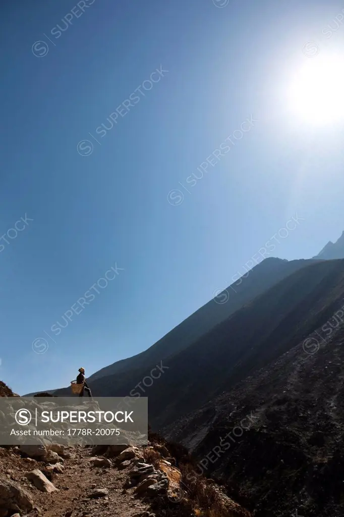 A Nepali woman stops en route to enjoy the view of the mountains.