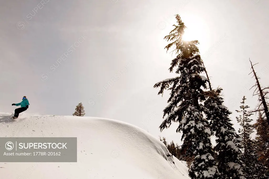 A female snowboarder lays out some fresh tracks while snowboarding in Squaw Valley, California.