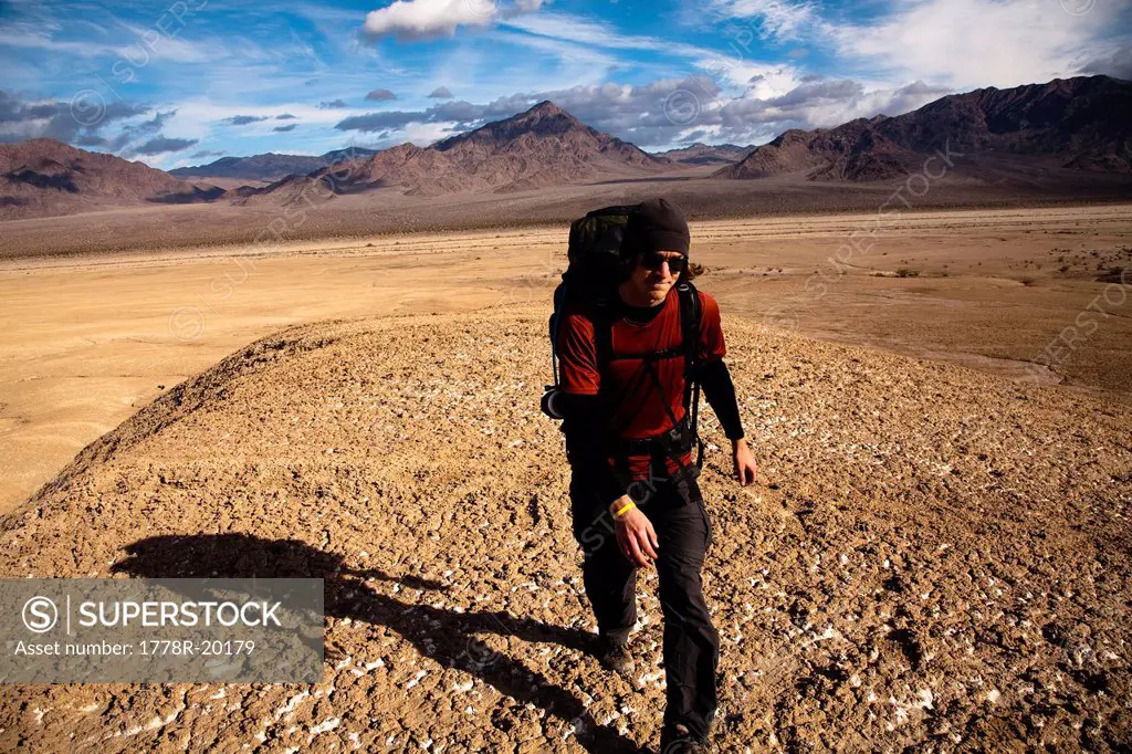 A young man backpacks through the Confidence Hills in Death Valley Nation Park, California.