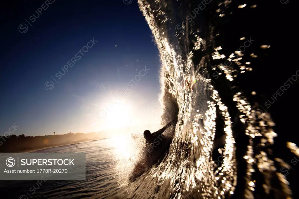 A male surfer pulls into a barrel at Zuma beach in Malibu, California.