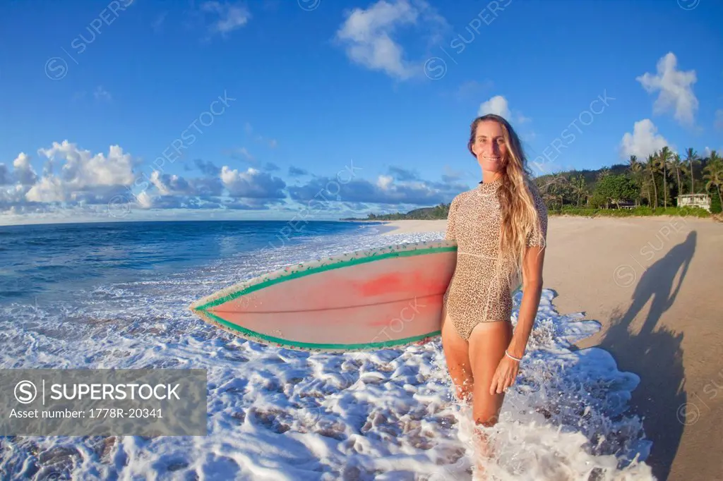 Surfer girl walking along the beach at Ehukai beach park.