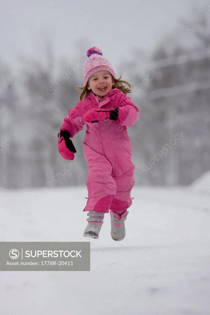 A young girl runs along a snow_covered road.