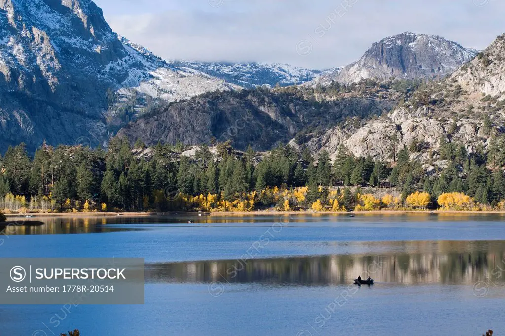 Two fishermen in a boat on a mountain lake with autumn leaves in the Sierra mountains of California