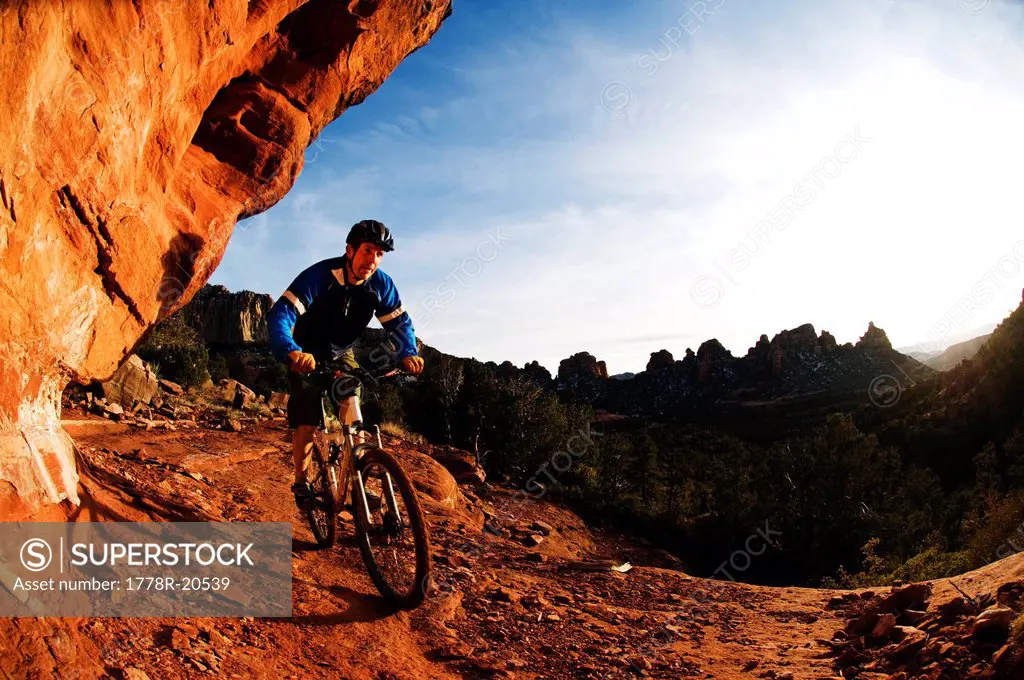 A man taking a bike ride on a rocky trail.