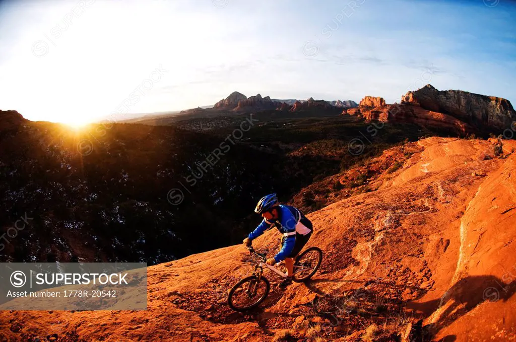 A middle age man rides his mountain bike through the red rock country around Sedona, Az at sunset.