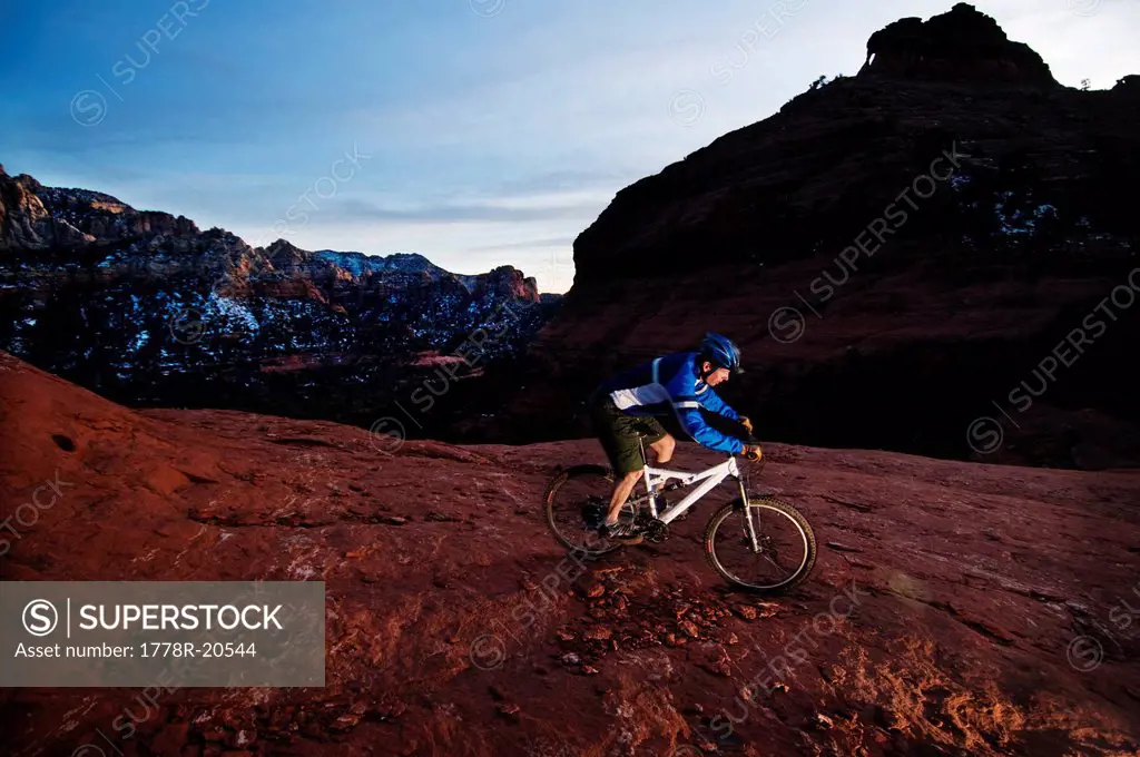 A middle age man rides his mountain bike through the red rock country around Sedona, Az at sunset.