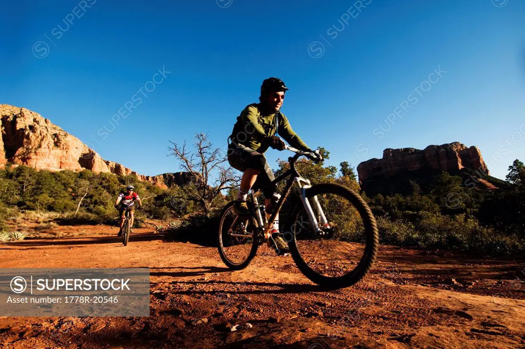 Two middle age men ride mountain bikes through the red rock country of Sedona, AZ.