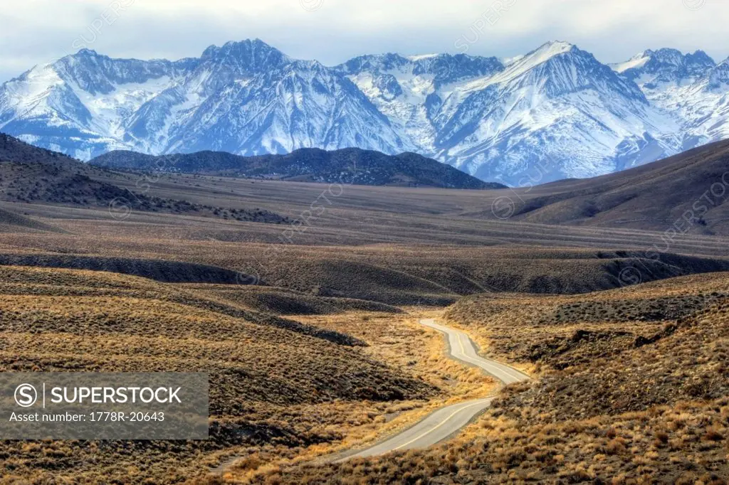 A road winds through the desert towards the Eastern Sierra Nevada mountain range in California.