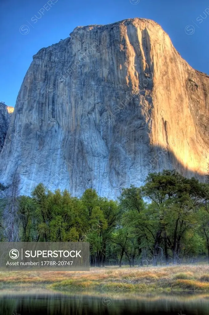 Looking over the Merced River, early morning sunlight hits El Capitan in Yosemite National Park, CA.