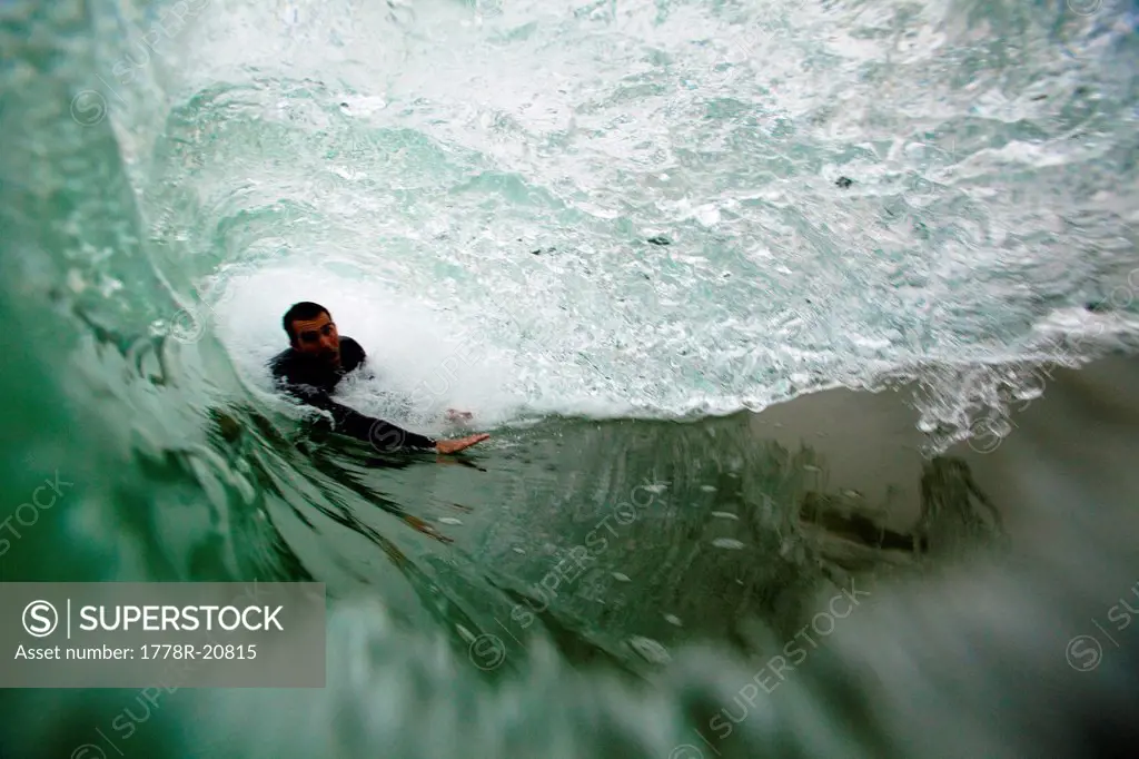 A male bodysurfer gets barreled while bodysurfing at Zuma beach in Malibu, California.