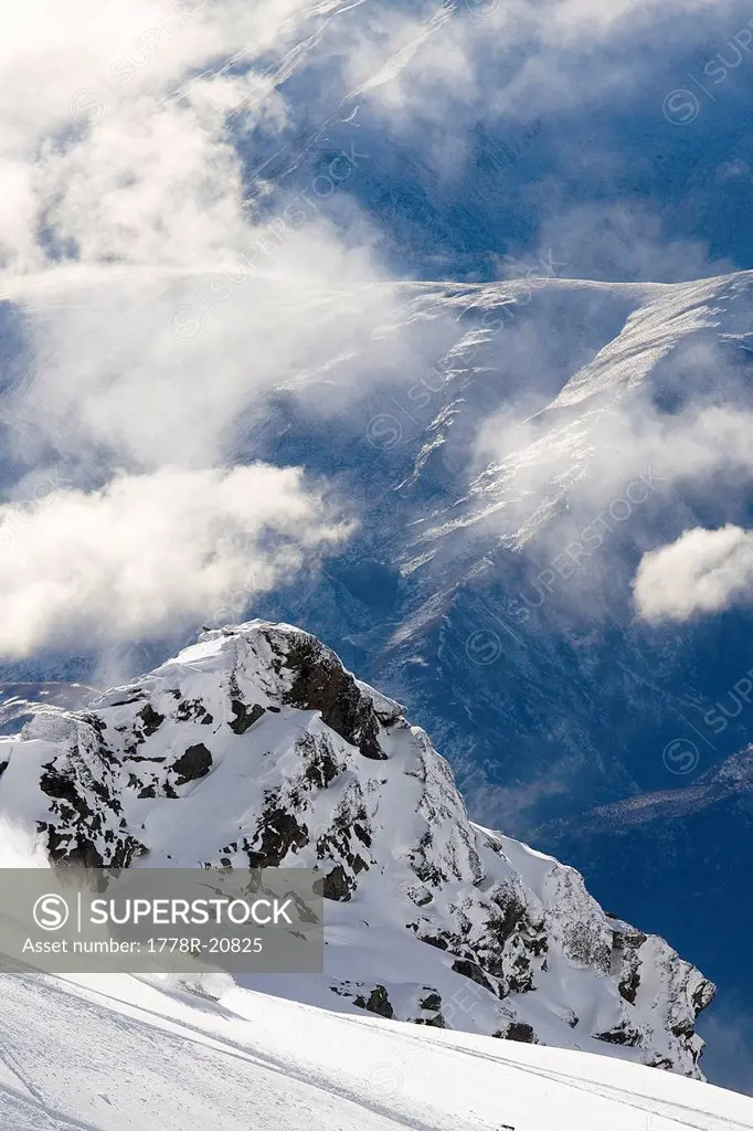 A male snowboarder rips a turn in deep powder while snowboarding on a mountain range in Queenstown, New Zealand.