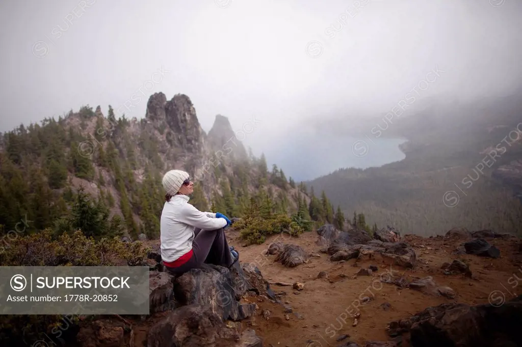 A young woman rests after hiking around the rim of Newberry Volcano east of the Cascade range near Bend, Oregon