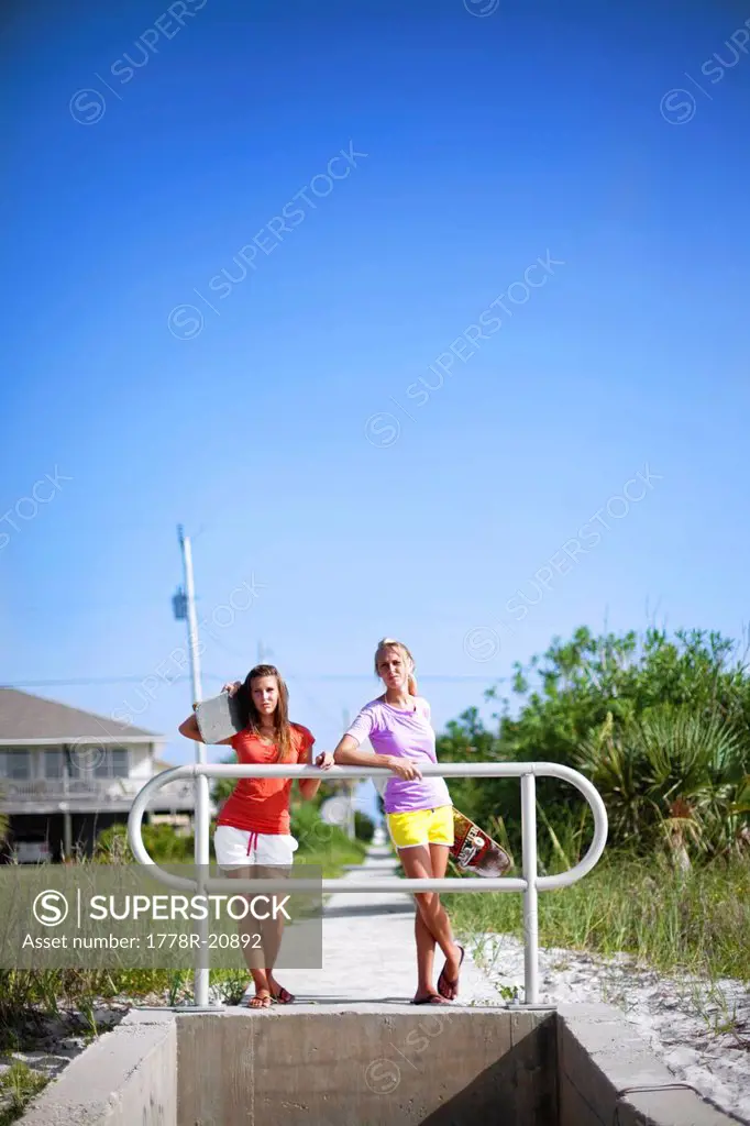 Two girls rest with their skateboards as they look out over the Santa Rosa Sound in Pensacola Beach, Florida.