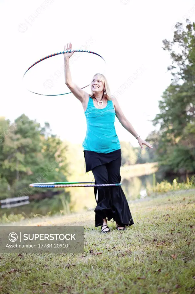 A mature woman twirls a hula hoop over her head and around her leg while exercising in Chelsea, Alabama.