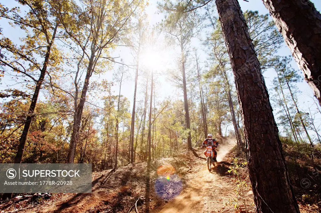 A motorcyclist rides a dirt trial on top of a hill in an Enduro race in Maplesville, Alabama. Back Lit, Lens Flare, Motion Blur