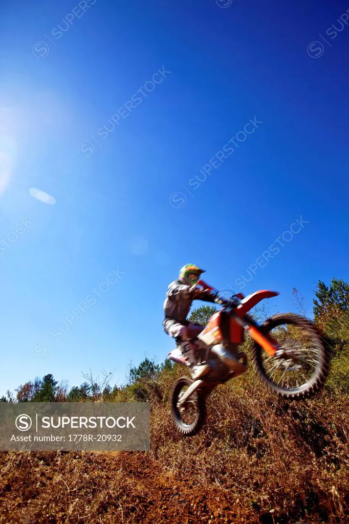 A motorcyclist catches air on a jump during an Enduro race in Maplesville, Alabama. Back lit, Lens Flare, Motion Blur