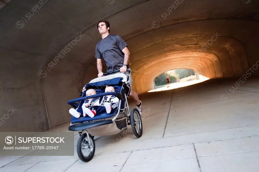 A man exiting a tunnel, running with his twin boys in a stroller in Helena, Alabama.
