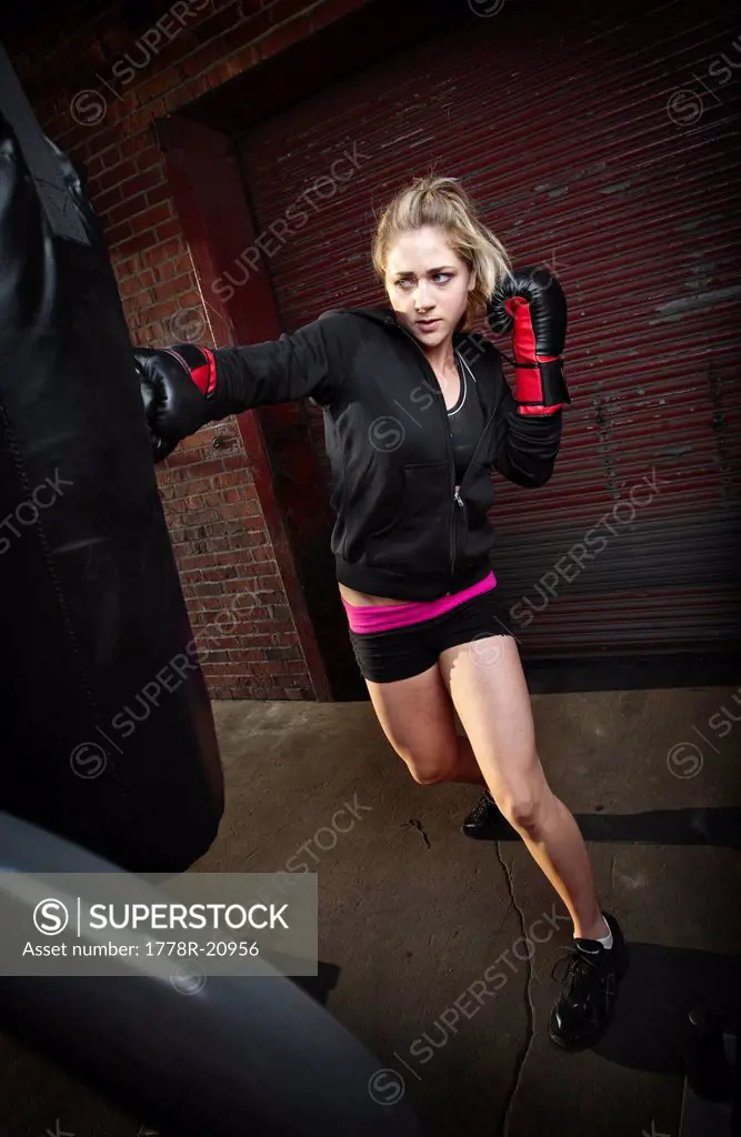 A teenage girl punches a punching bag while training for mixed martial arts outside a warehouse in Birmingham, Alabama.
