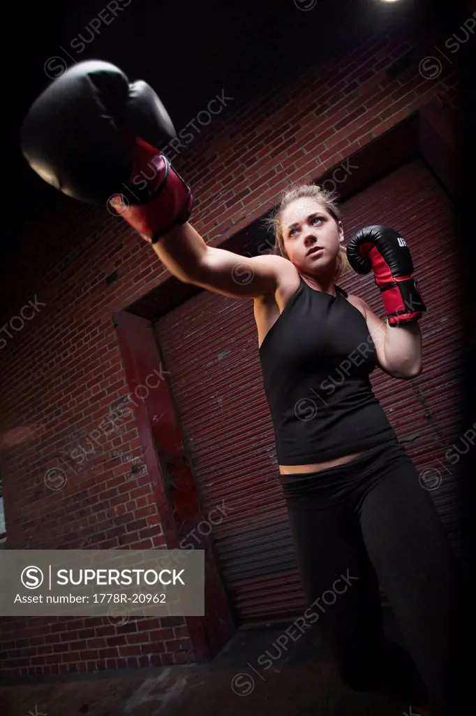 A teenage girl practices punching while training for mixed martial arts outside a warehouse in Birmingham, Alabama.