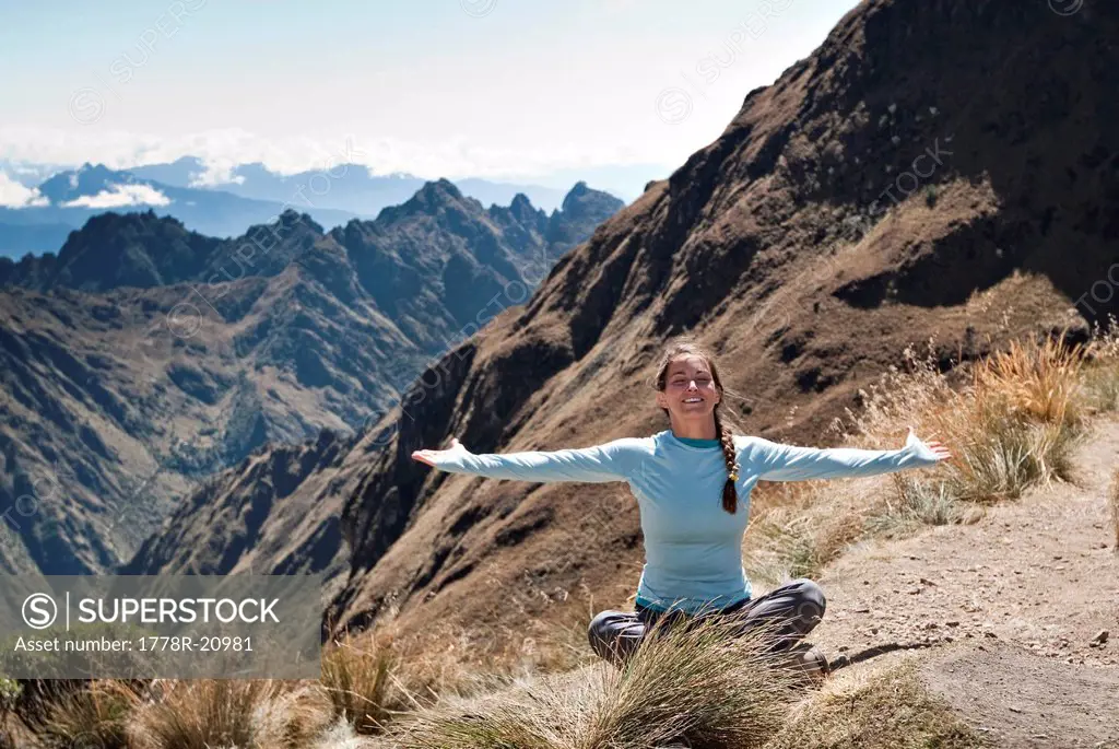 A young woman enjoys a beautiful moment and breathes in the fresh air while on Dead Woman´s Pass, Inca Trail.