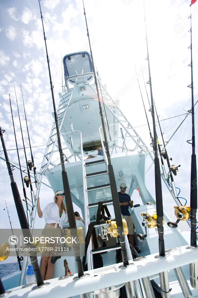 A wide angle view of a fully equipped deep sea fishing boat with rods in the foreground .