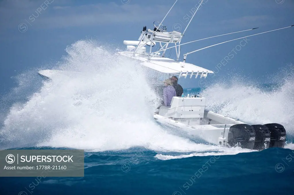 A fishing boat speeds through the blue surf spraying white water.