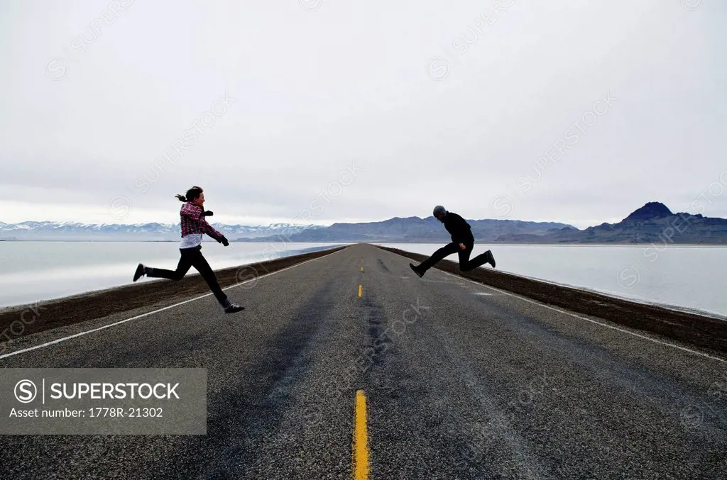 A couple jump on a long and lonesome road in West Wendover, Utah.