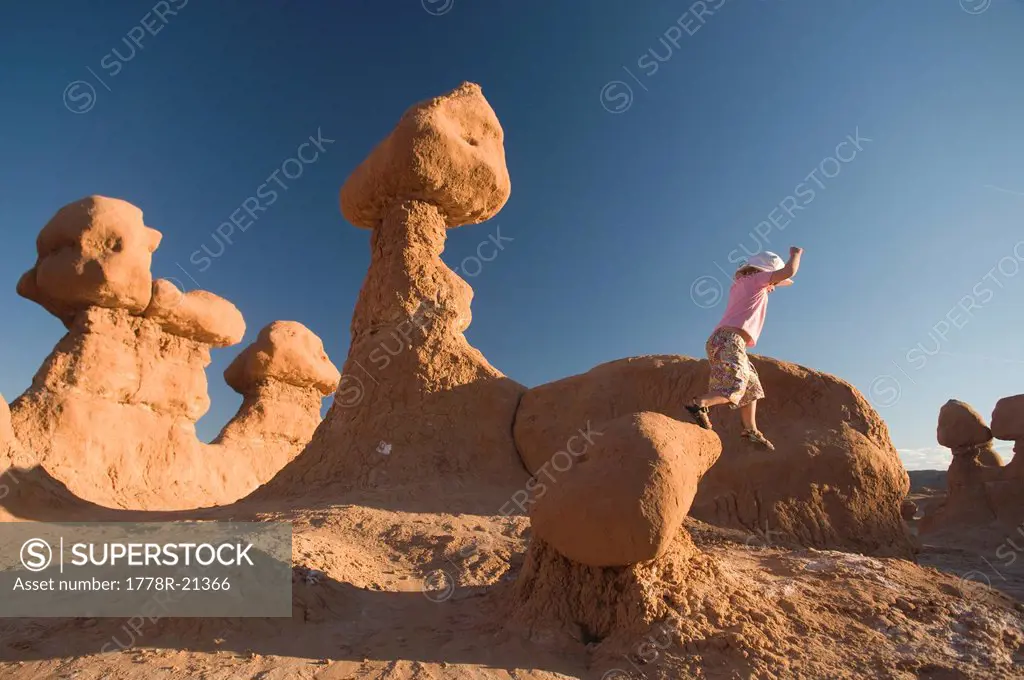 Young girl jumping off rocks in Goblin Valley State Park, Hanksville, Utah.