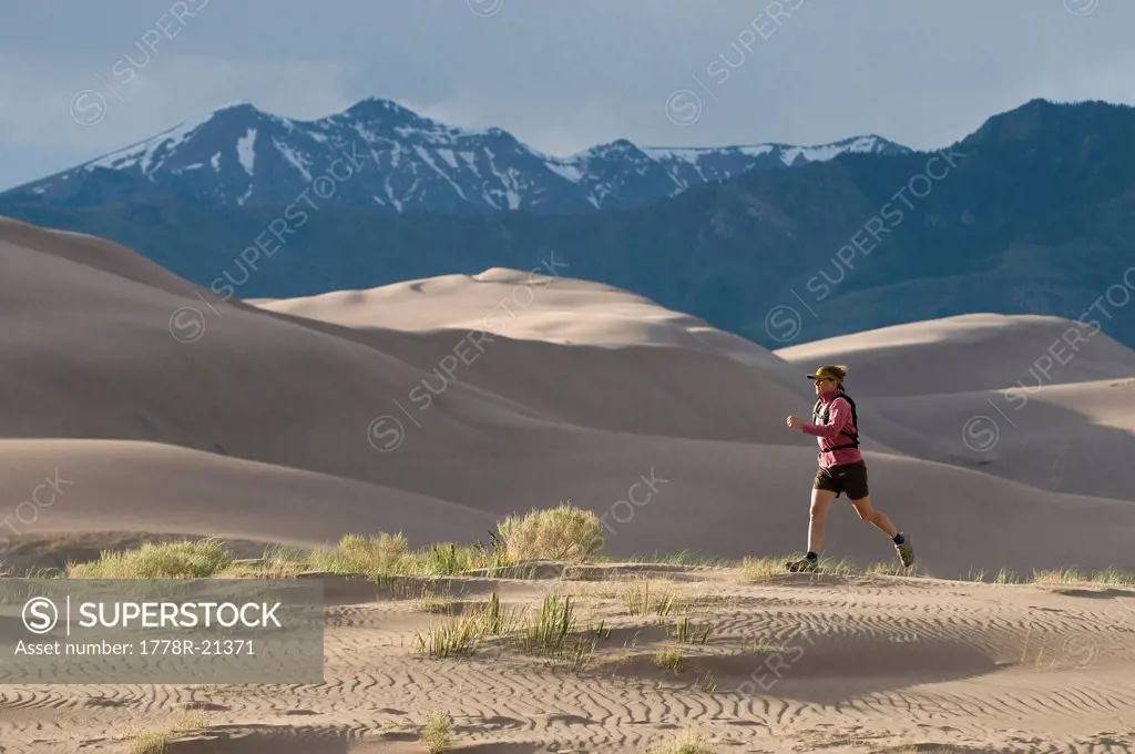 Woman running through sand dunes, Great Sand Dunes National Park, Alamosa, Colorado.