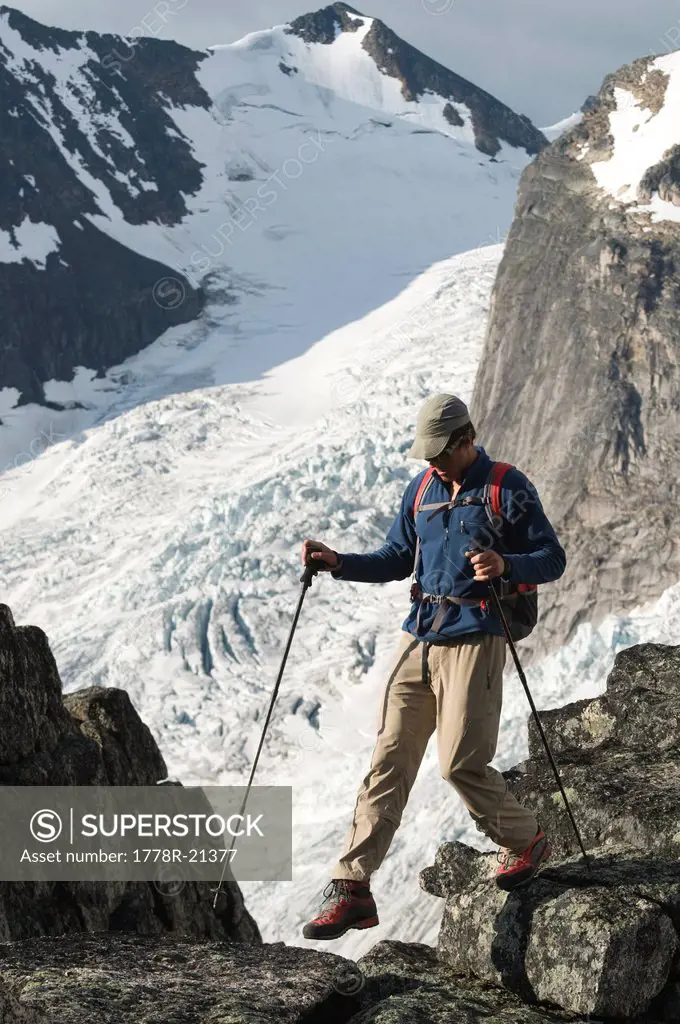 Man hiking through granite and glaciers while mountaineering, Bugaboo Provincial Park, Radium, British Columbia, Canada.