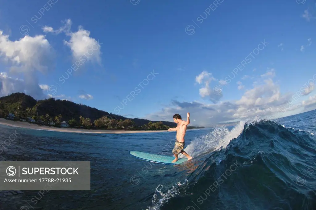 A young man surfing at Monster Mush, on the north shore of Oahu, Hawaii.