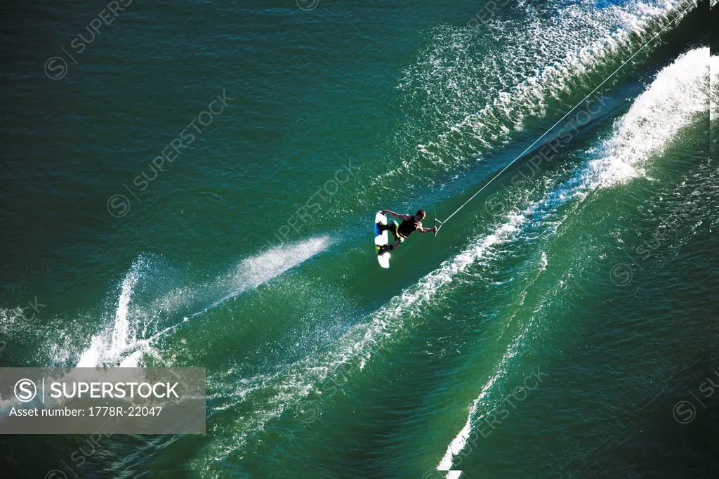A athletic wakeboarder jumps the wake going huge on a calm day in Idaho.