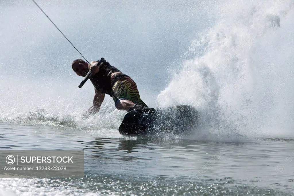A athletic man wakeboarding slashes a wave in Idaho.