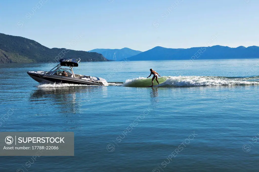 A sexy woman wakesurfs behind a wakeboard boat on a sunny day in Idaho.