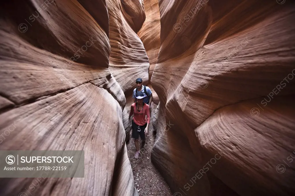 A couple hiking through a slot canyon in Utah.