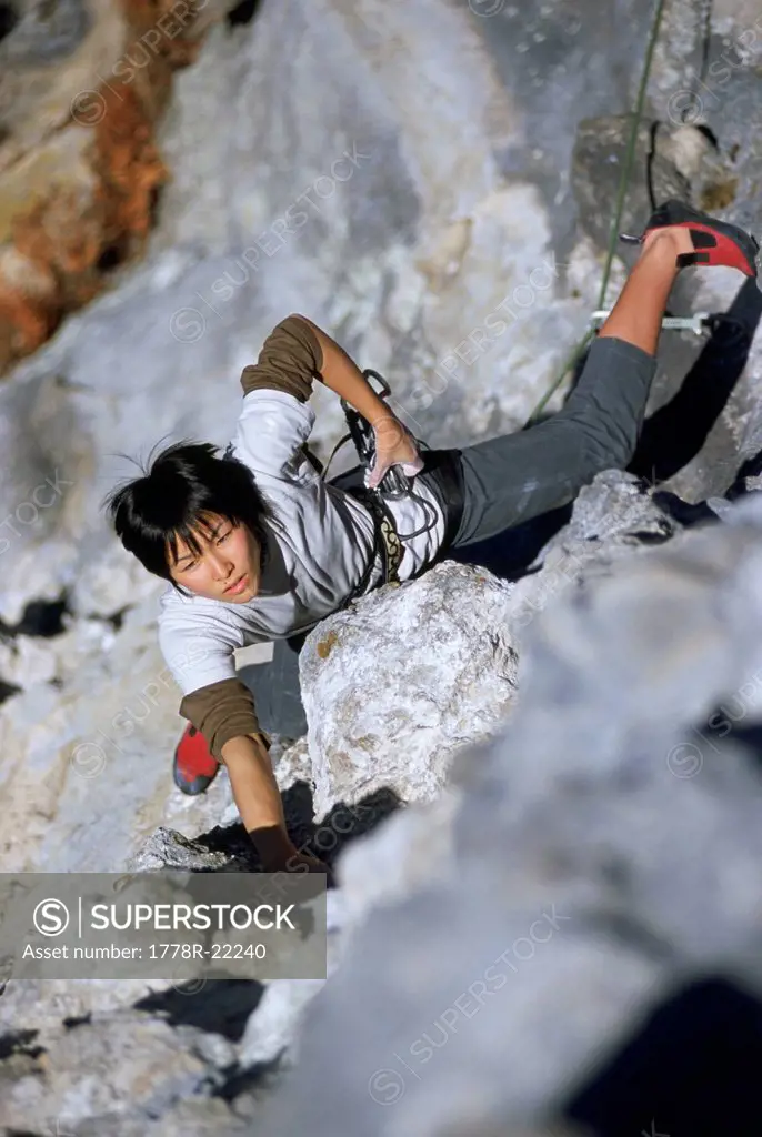 A girl climbs steep rock in Japan.